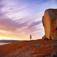 Red sculpted rock formations against a blue and lilac sky with scattered white clouds