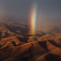 A four-wheel-drive on a dusty outback road against a background of mountain ranges at dusk