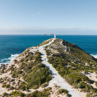 The sea gently rolling into white crests at a sandy beach and rocky coastline on a sunny day